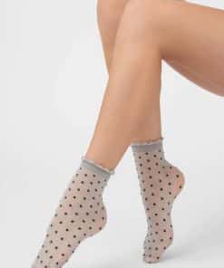 Woman's legs wearing sheer beige polka-dot socks with lace trim at the ankles.