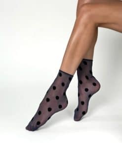 Sheer black polka dot tights worn on legs, photographed mid-step against a white background.