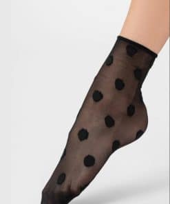 Sheer black sock with large polka dots on a foot, ankle height and semi-transparent fabric