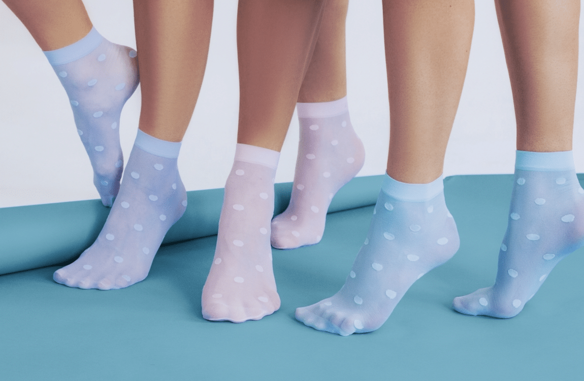 Several legs in pastel polka-dot socks standing on a blue mat.
