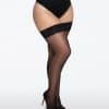 Lower body of a person wearing black stockings with a lace top and black high heels, standing sideways.