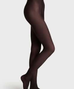 Full-length view of a person wearing dark brown sheer tights, shown in profile with one leg crossed in front of the other.