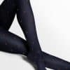 Navy polka-dot tights worn on legs, crossed at the knee, against a white background.