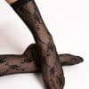 Two feet in black lace stockings crossed over each other, posing against a white background.