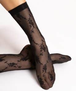 Two feet in black lace stockings crossed over each other, posing against a white background.