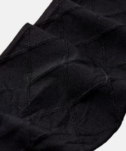Close-up of black fabric with a subtle diamond stitch pattern, likely a knitted textile or sock material.